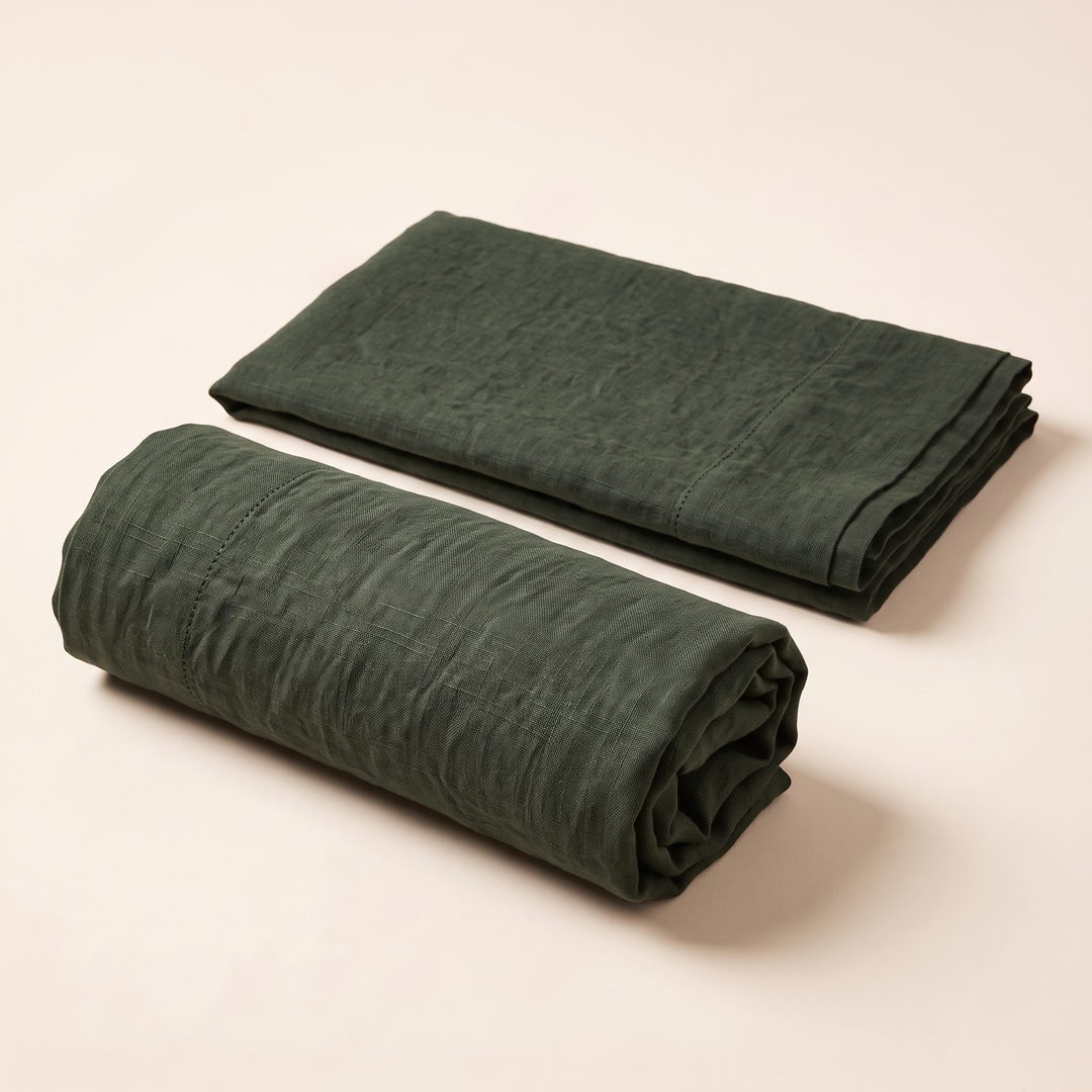 Linen Pillowcases – Set of 2 in Forest Green – one rolled up and one folded flat on plain cream background