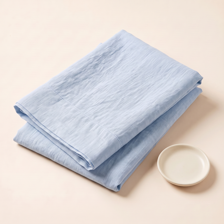 Linen Pillowcases – Set of 2 in Light Blue – folded stack beside a small round ceramic dish