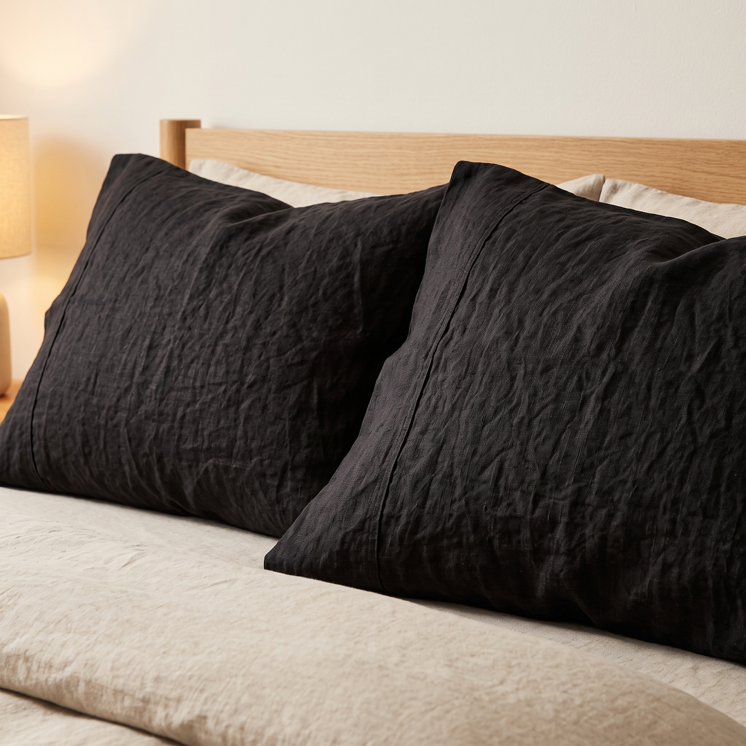Linen Pillowcases – Set of 2 in Black – two pillows propped against an oak headboard on a made bed