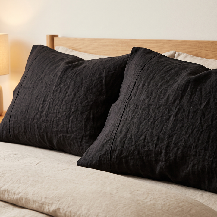 Linen Pillowcases – Set of 2 in Black – two pillows propped against an oak headboard on a made bed