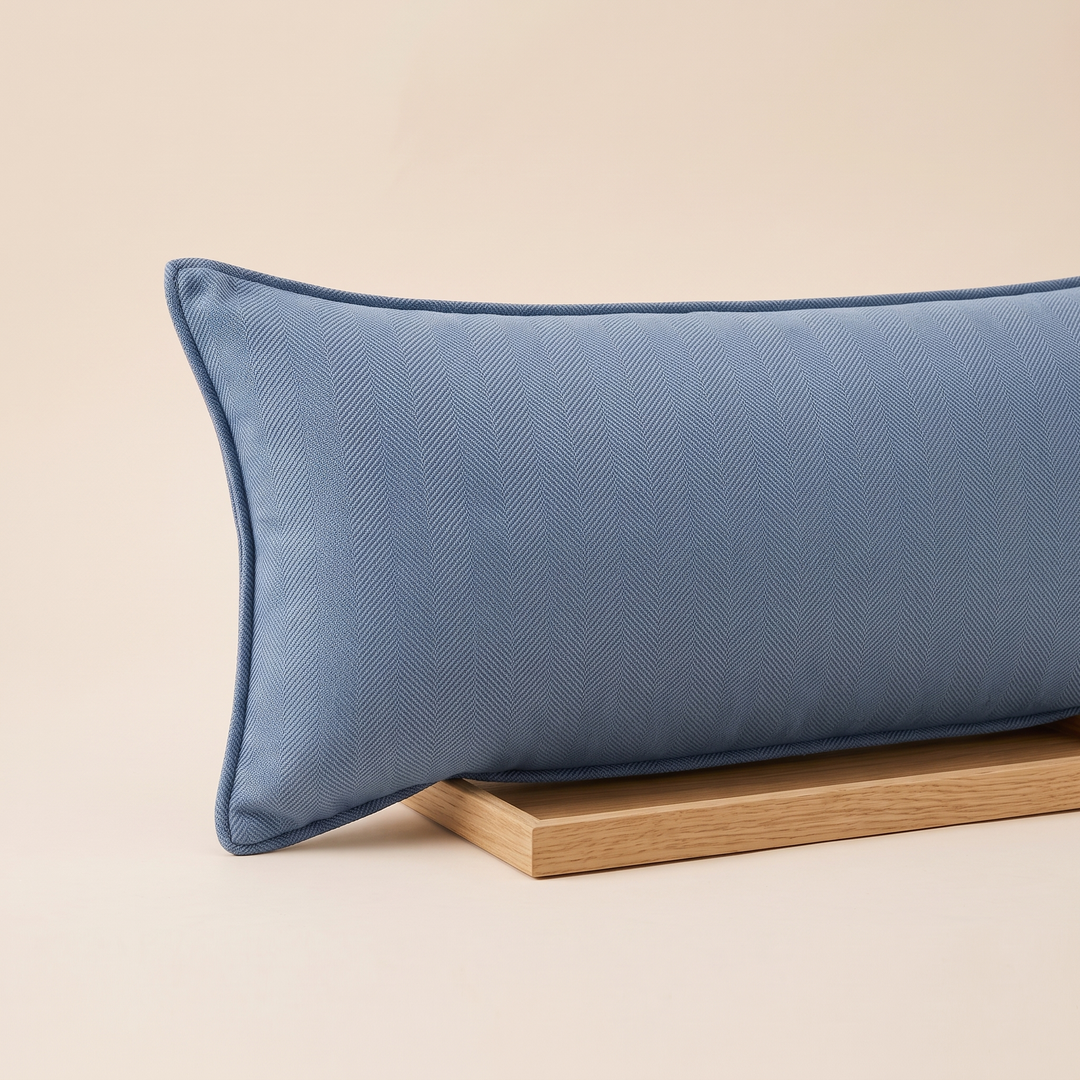 Long Lumbar Pillow Cover in Denim Blue – cropped left end resting on a slim light wood board