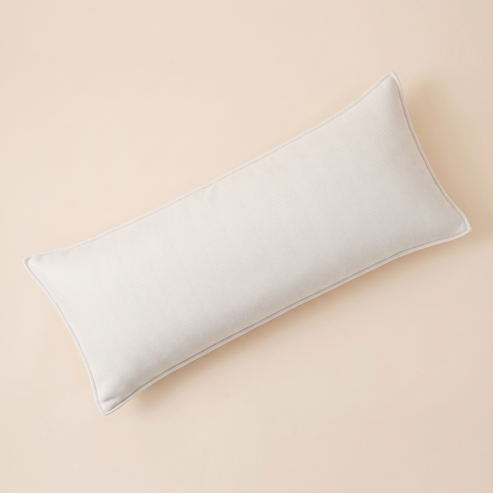 Long Lumbar Pillow Cover in White – laid flat at a diagonal on a peach background, seen from above