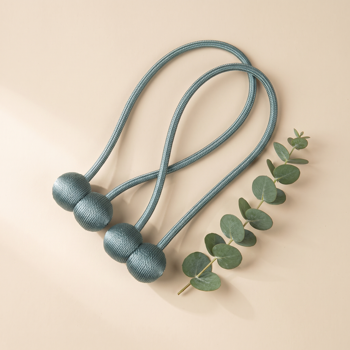 Magnetic Curtain Tiebacks – Set of 2 in Aqua – styled next to a eucalyptus sprig on a beige surface