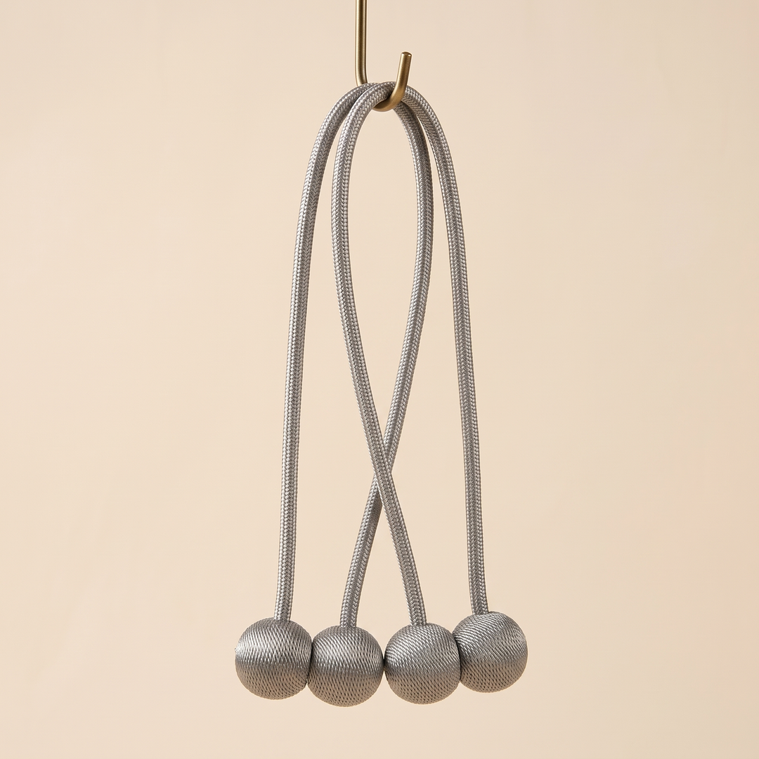 Magnetic Curtain Tiebacks – Set of 2 in Gray – hanging from a brass wall hook with the four balls dangling