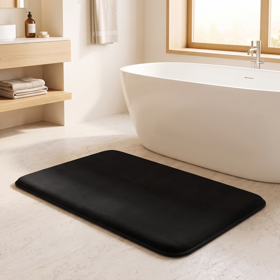 Non-Slip Memory Foam Bath Mat – Plush in Black – on a beige bathroom floor beside a freestanding white tub