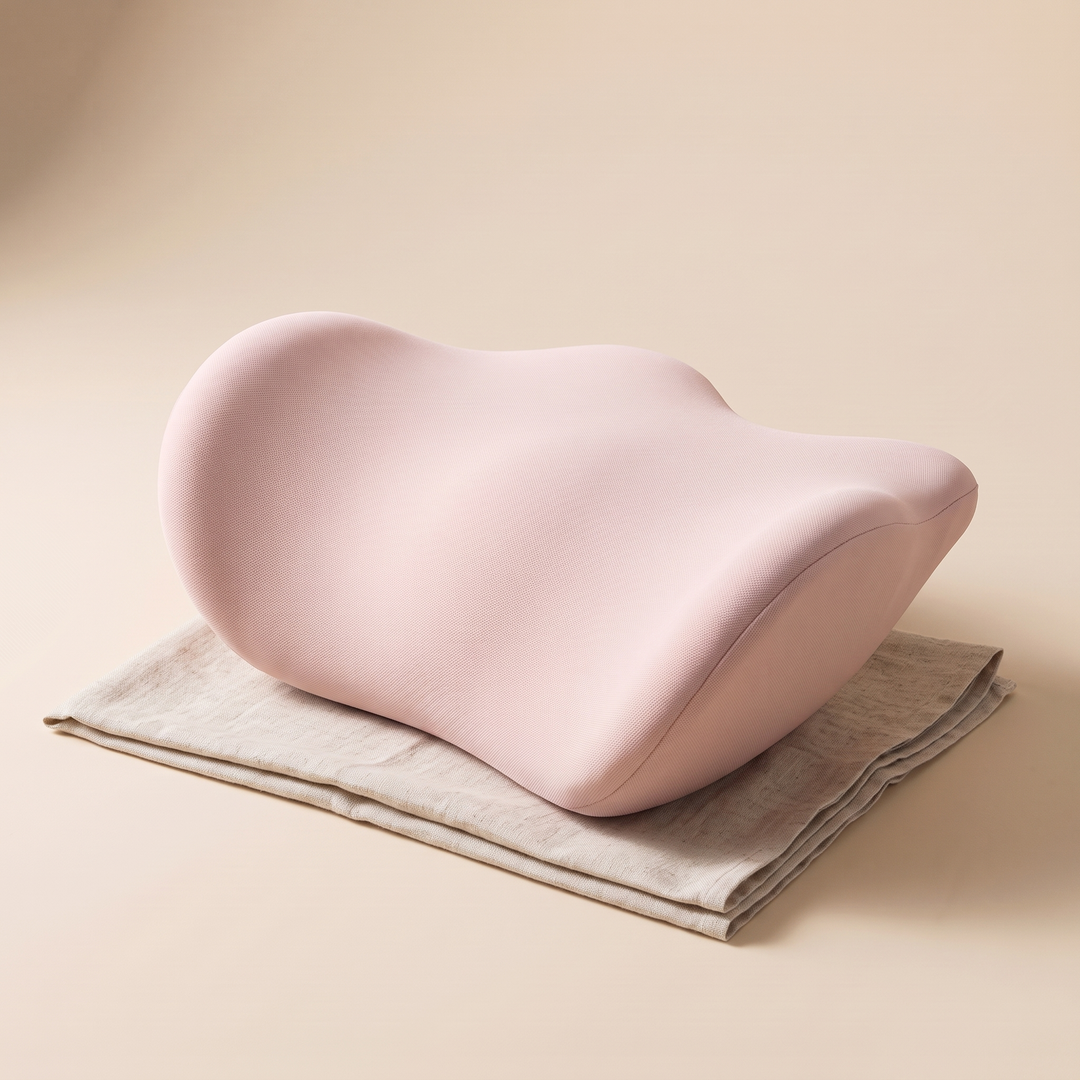 Memory Foam Lumbar Pillow in Light Pink – resting on a folded linen cloth against a beige backdrop