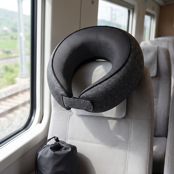 Memory Foam Neck Pillow for Travel in Dark Gray – hanging on a train seat headrest by a window