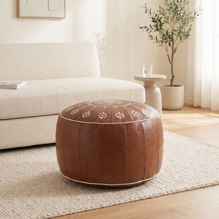 Moroccan Pouf Cover – Unstuffed in Brown – Embroidered – on a woven rug beside a cream sofa in a sunlit living room