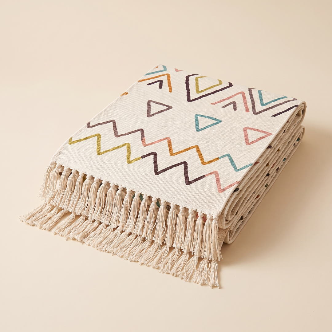 Moroccan-Style Rug with Tassels – Flat Woven in Cream Geometric – folded in a stack on a plain beige background