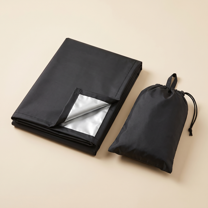 Outdoor Furniture Cover – Waterproof, Rectangular in Black – folded with one corner flipped to show silver lining, beside pouch