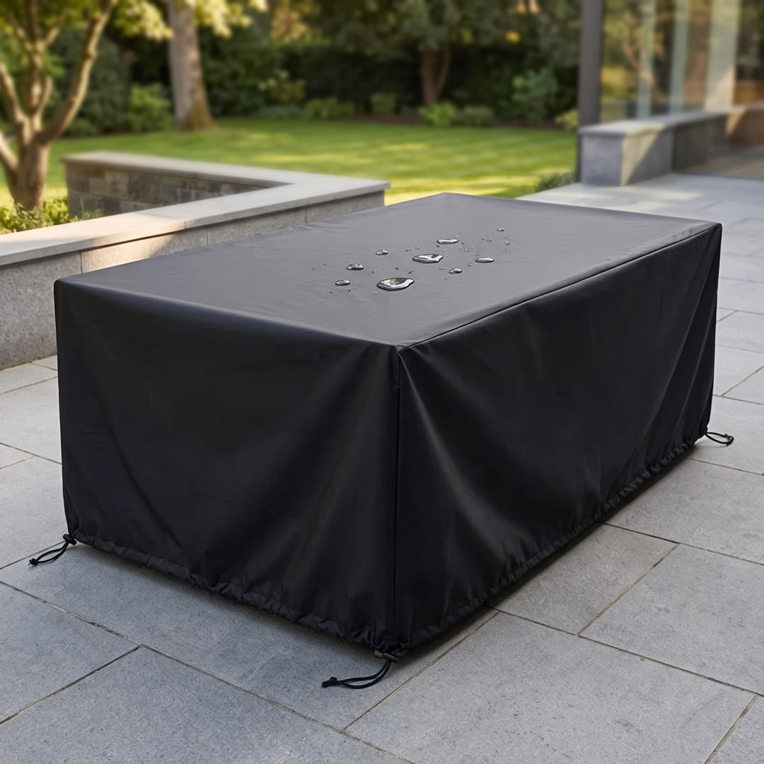 Outdoor Furniture Cover – Waterproof, Rectangular in Black – fitted over a patio table on stone paving by a lawn