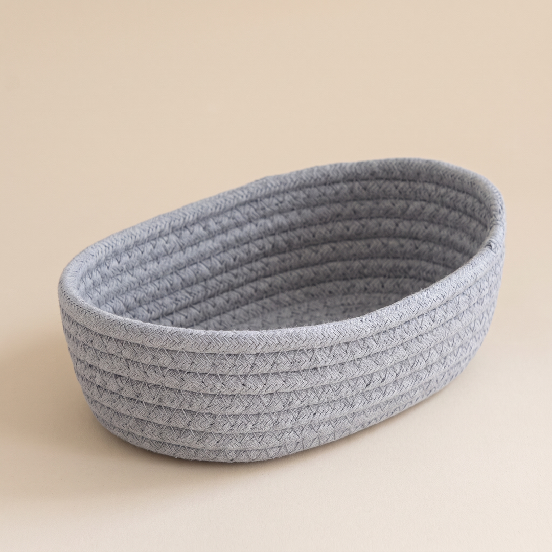 Oval Rope Basket – Cotton Rope in Light Gray – empty, viewed from above at an angle, on a plain beige backdrop