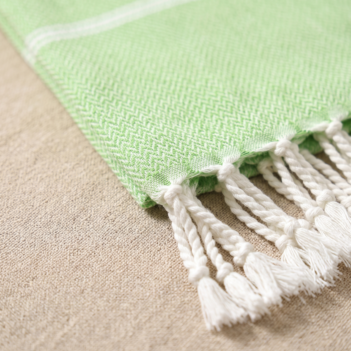 Oversized Beach Towel with Tassels in Light Green – close-up of herringbone weave and knotted fringe on a linen surface