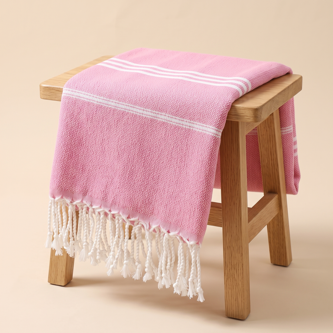 Oversized Beach Towel with Tassels in Pink – draped over a wooden stool against a peach backdrop
