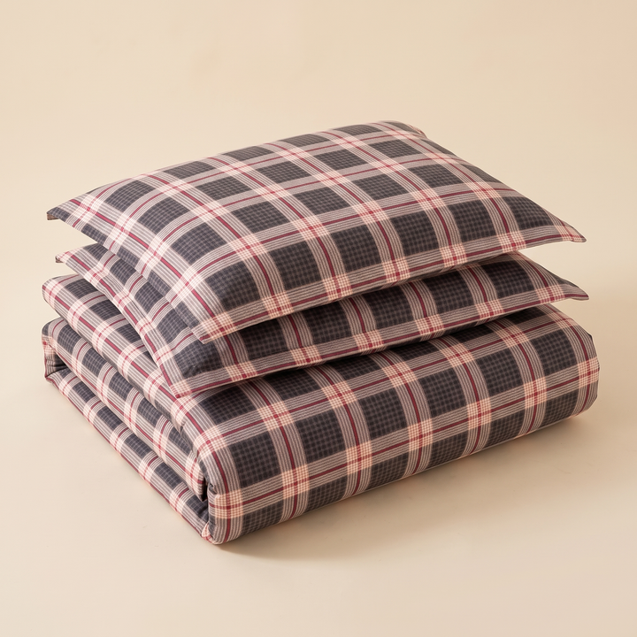 Plaid Bedding Set in Charcoal Plaid – folded duvet cover topped with two pillowcases stacked on a plain beige background