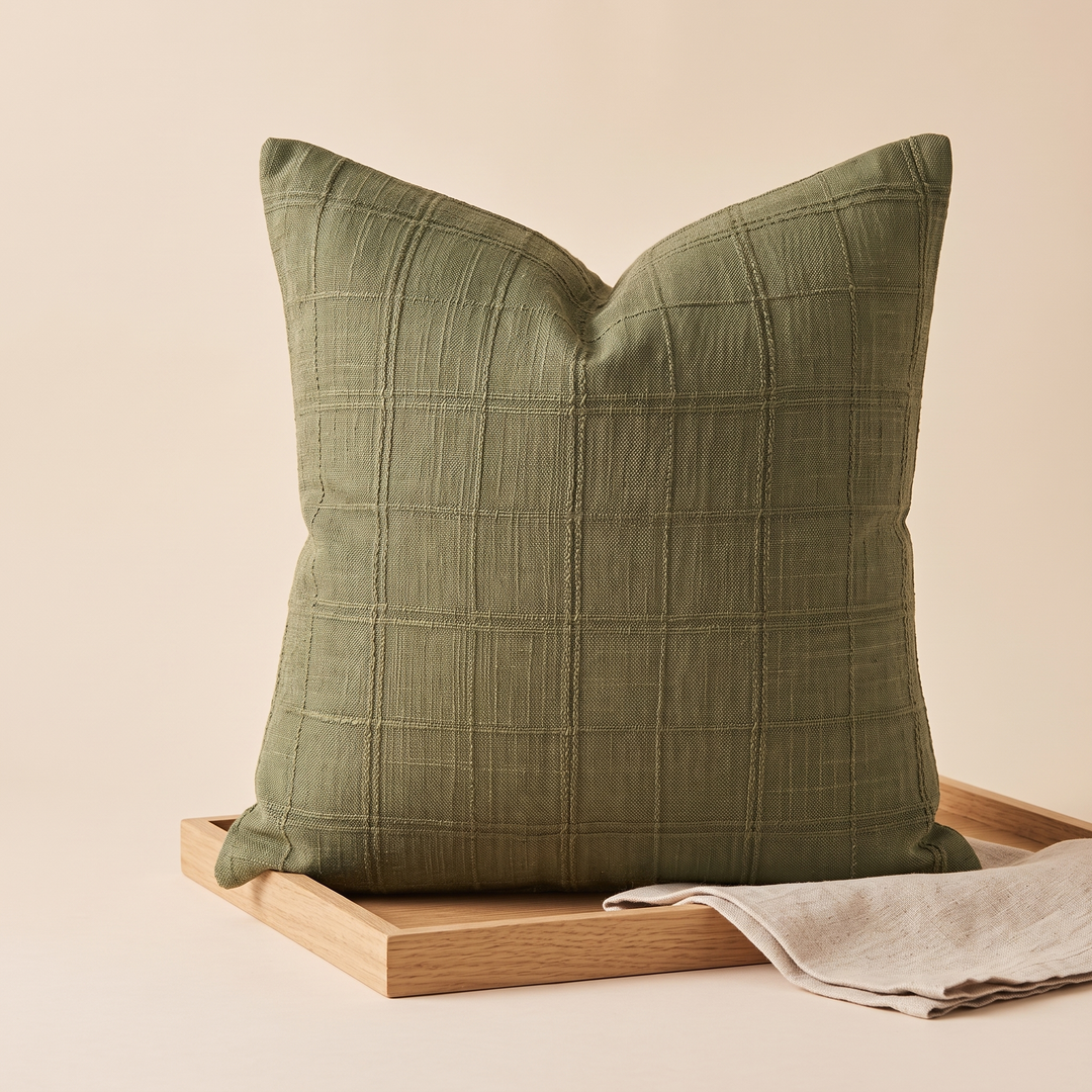 Plaid Pillow Cover – Textured Grid Check in Olive Green – propped on a wooden tray with a folded linen cloth