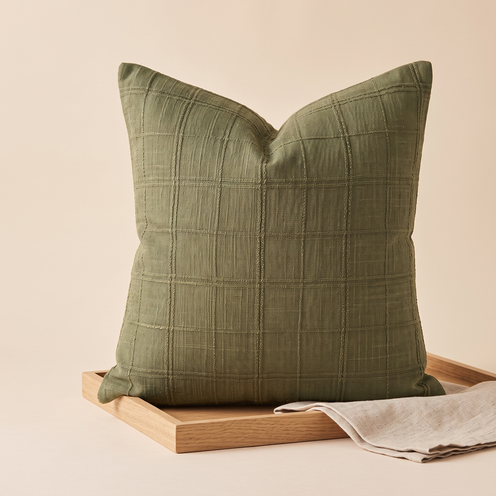 Plaid Pillow Cover – Textured Grid Check in Olive Green – propped on a wooden tray with a folded linen cloth