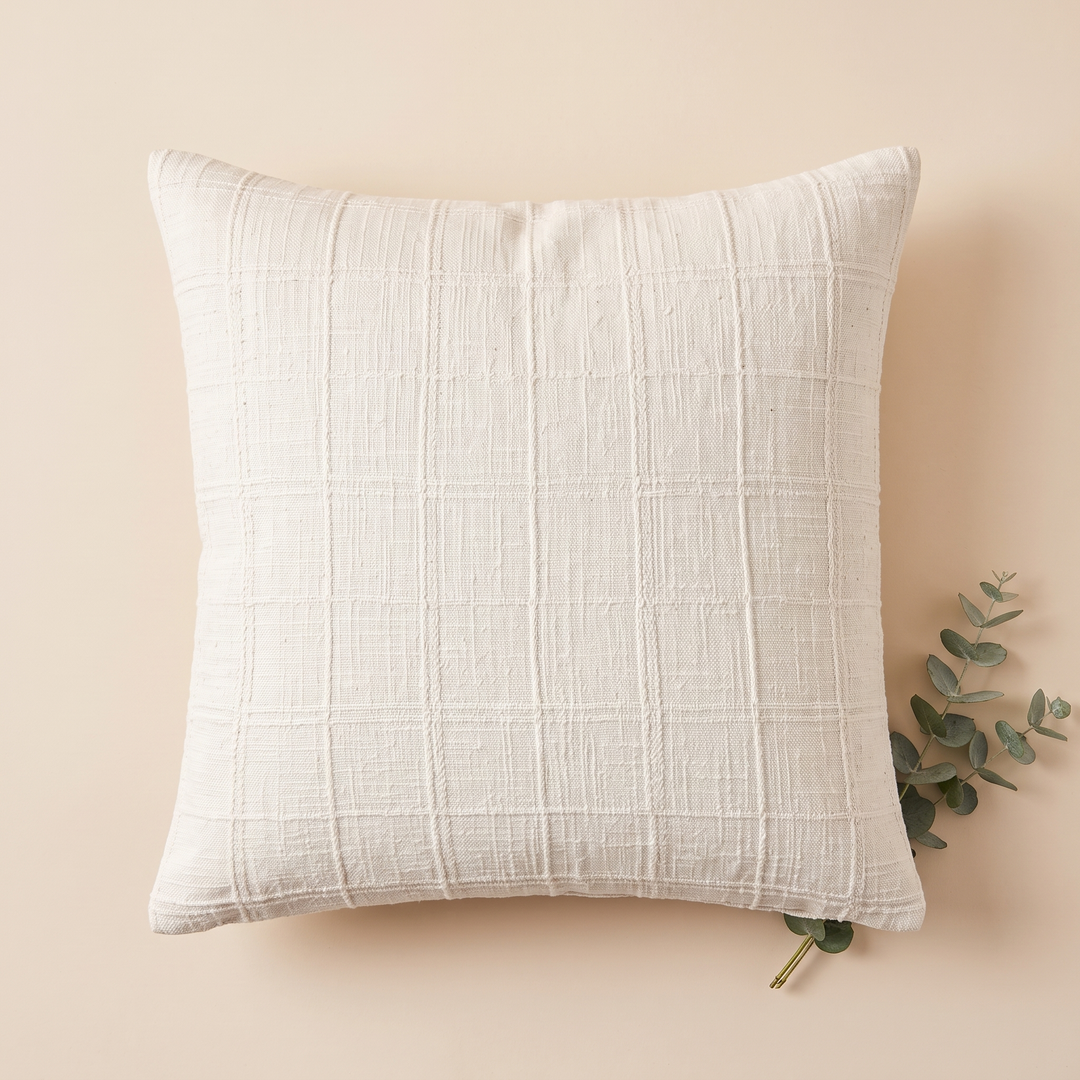 Plaid Pillow Cover – Textured Grid Check in White – flat lay from above with a eucalyptus sprig on peach