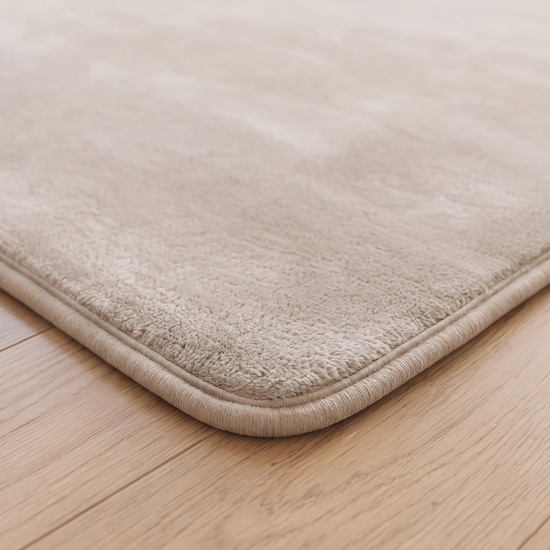 Plush Area Rug in Beige – close-up of a rounded corner and bound edge on wood flooring