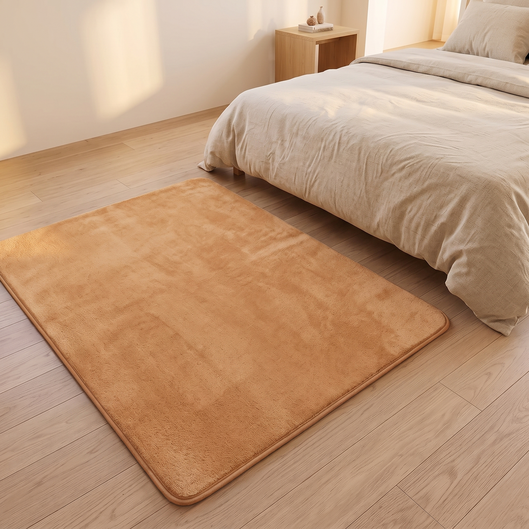 Plush Area Rug in Camel – beside a bed with linen bedding on a wood floor