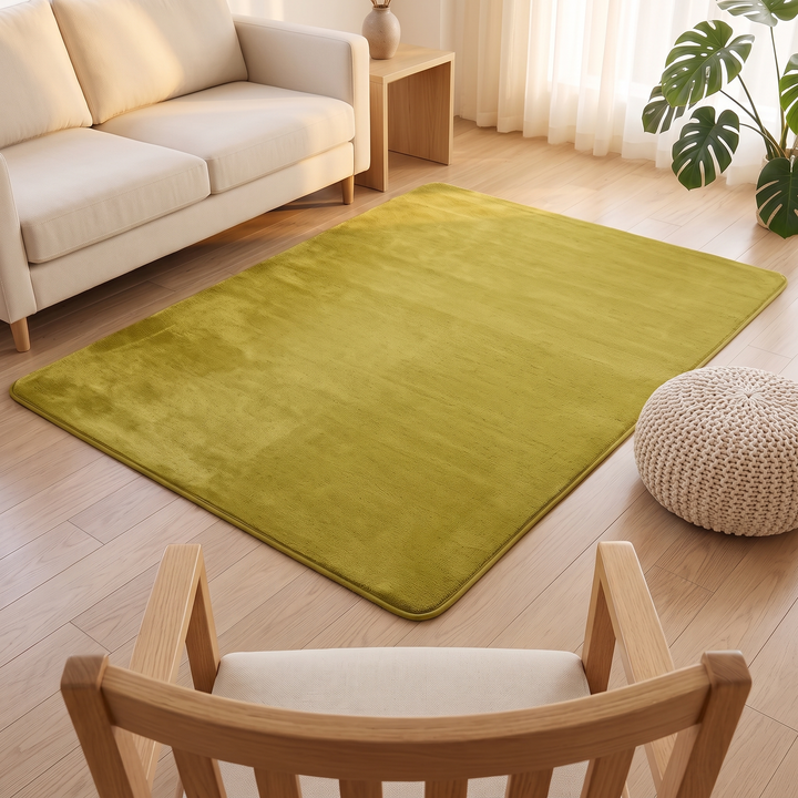 Plush Area Rug in Moss Green – viewed over a wooden chair back beside a knitted pouf