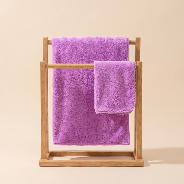Plush Bath Towel Set – 2 Piece in Violet – hanging on a freestanding wooden rack against a beige studio backdrop