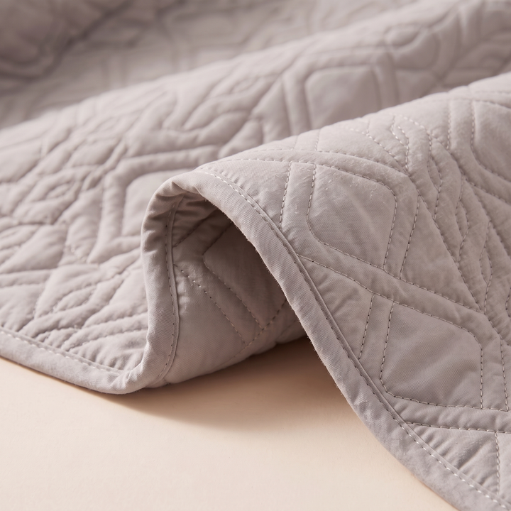 Close-up of the gray diamond quilting and stitched edge
