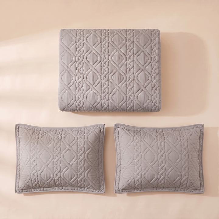 Gray diamond quilted bedspread folded with its 2 pillow shams