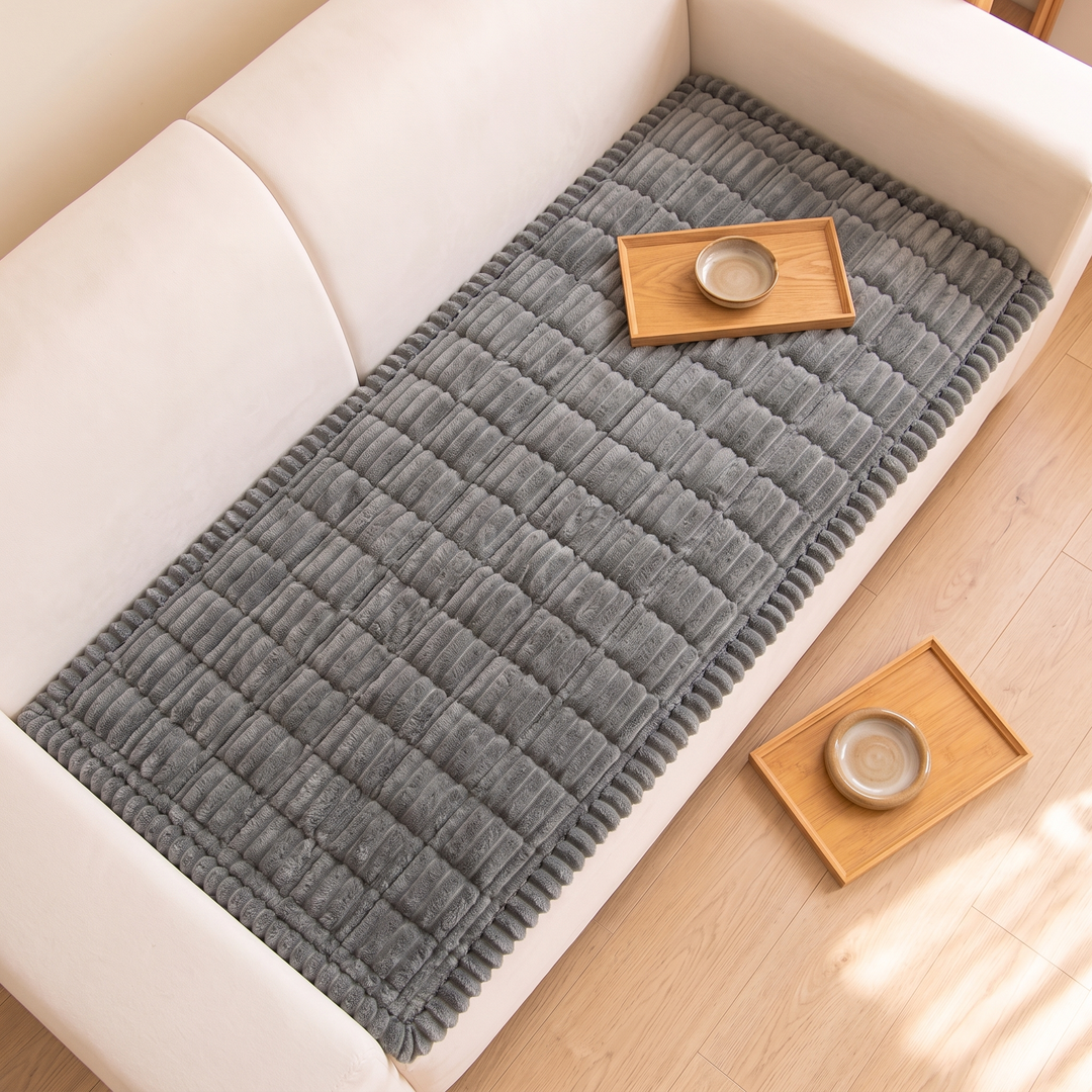 Quilted Plush Couch Cover – Ribbed in Charcoal – overhead view on a sofa with two wooden trays