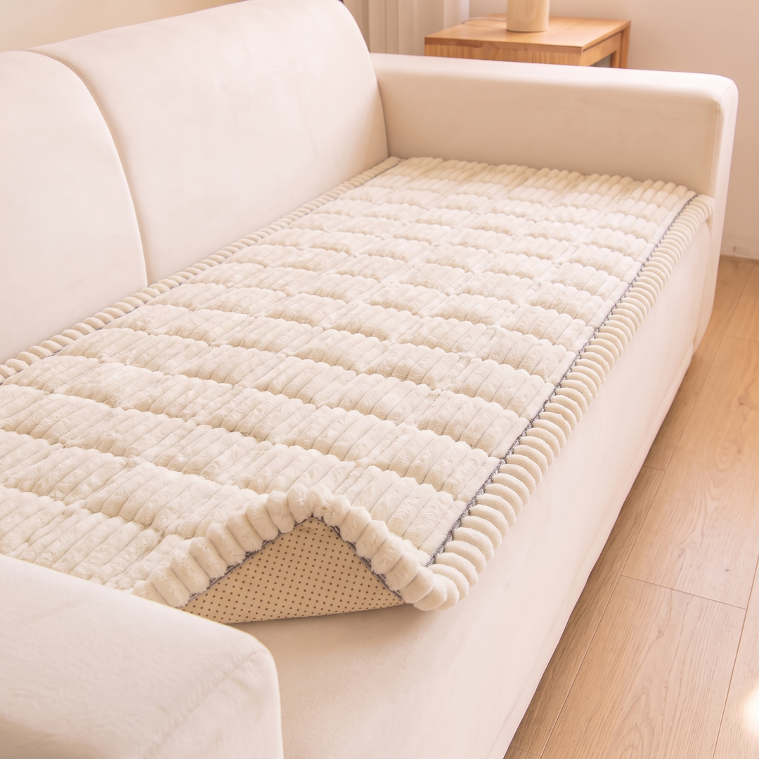 Quilted Plush Couch Cover – Ribbed in Cream – angled view on a sofa beside a wooden side table