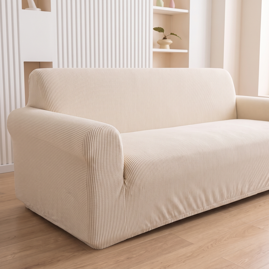Ribbed Stretch Couch Cover in Cream – three-quarter side view against slatted wall with plant shelf