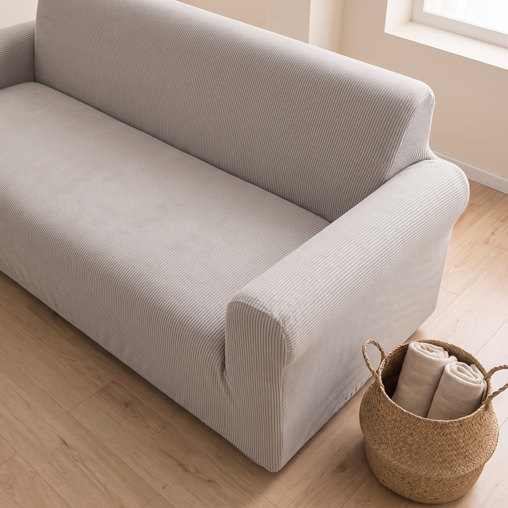 Ribbed Stretch Couch Cover in Light Gray – overhead angle beside a woven basket on a wood floor