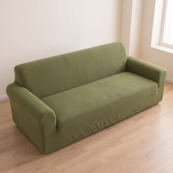 Ribbed Stretch Couch Cover in Olive Green – front corner view beside a window and cream wall