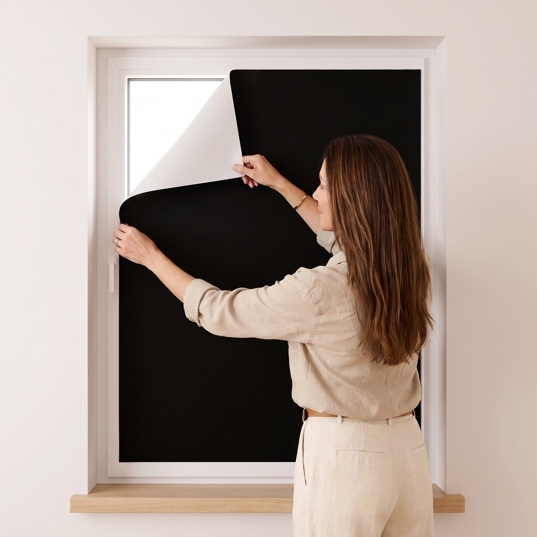 Room-Darkening Window Cover – Cut to Size in Black – woman in linen shirt fitting it to a window