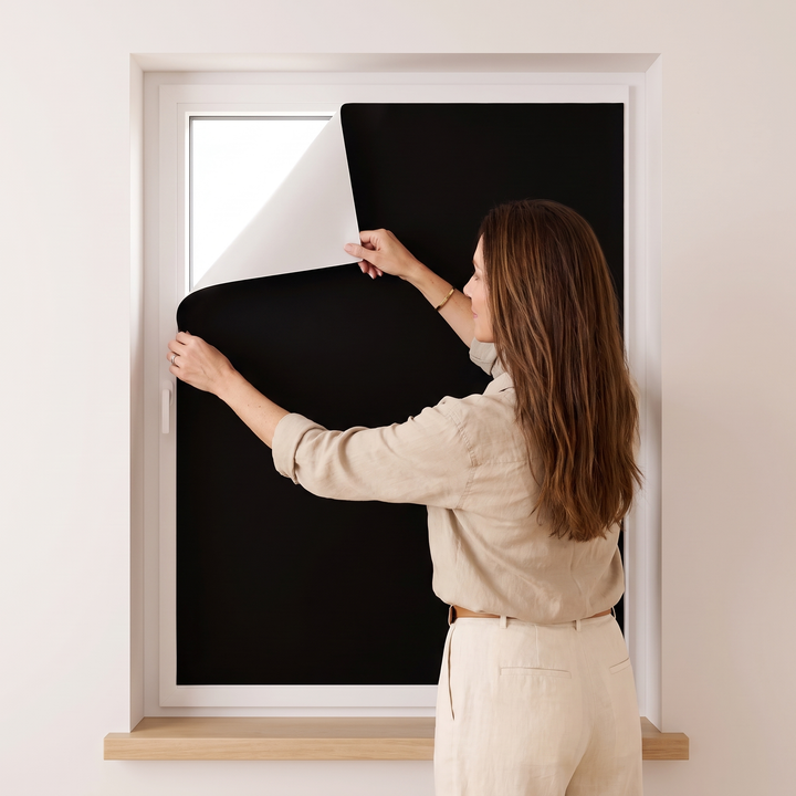 Room-Darkening Window Cover – Cut to Size in Black – woman in linen shirt fitting it to a window