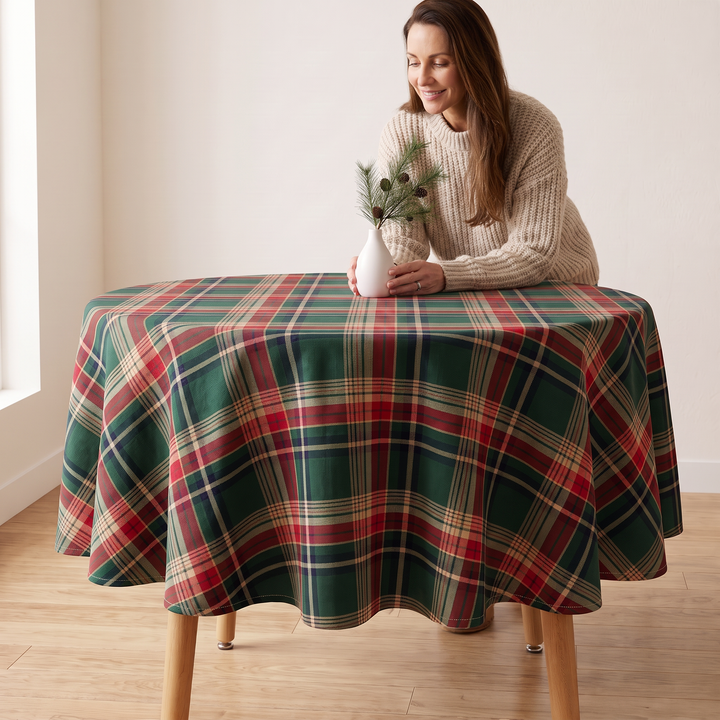 Round Christmas Tablecloth – Plaid in Green Tartan – woman in cream sweater leaning on table in bright room