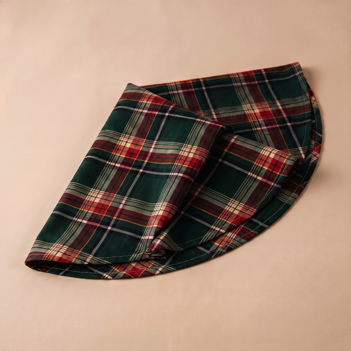 Round Christmas Tablecloth – Plaid in Green Tartan – folded in half on a plain beige background