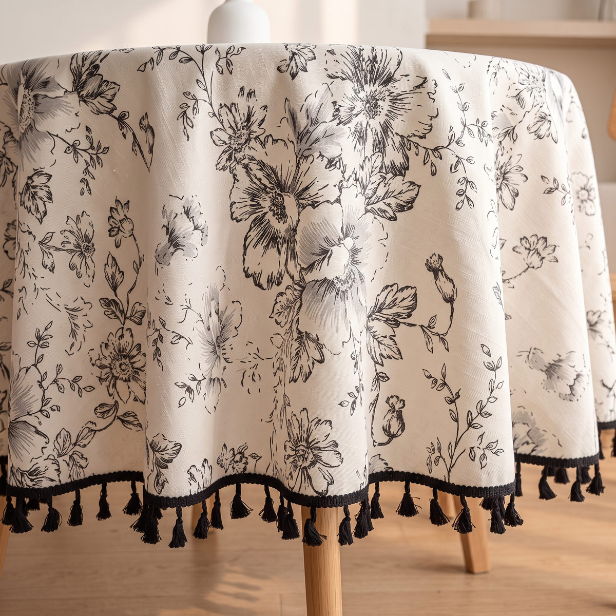 Round Floral Tablecloth in Black Floral – Tassels – close-up of tassel hem draping over wooden table legs