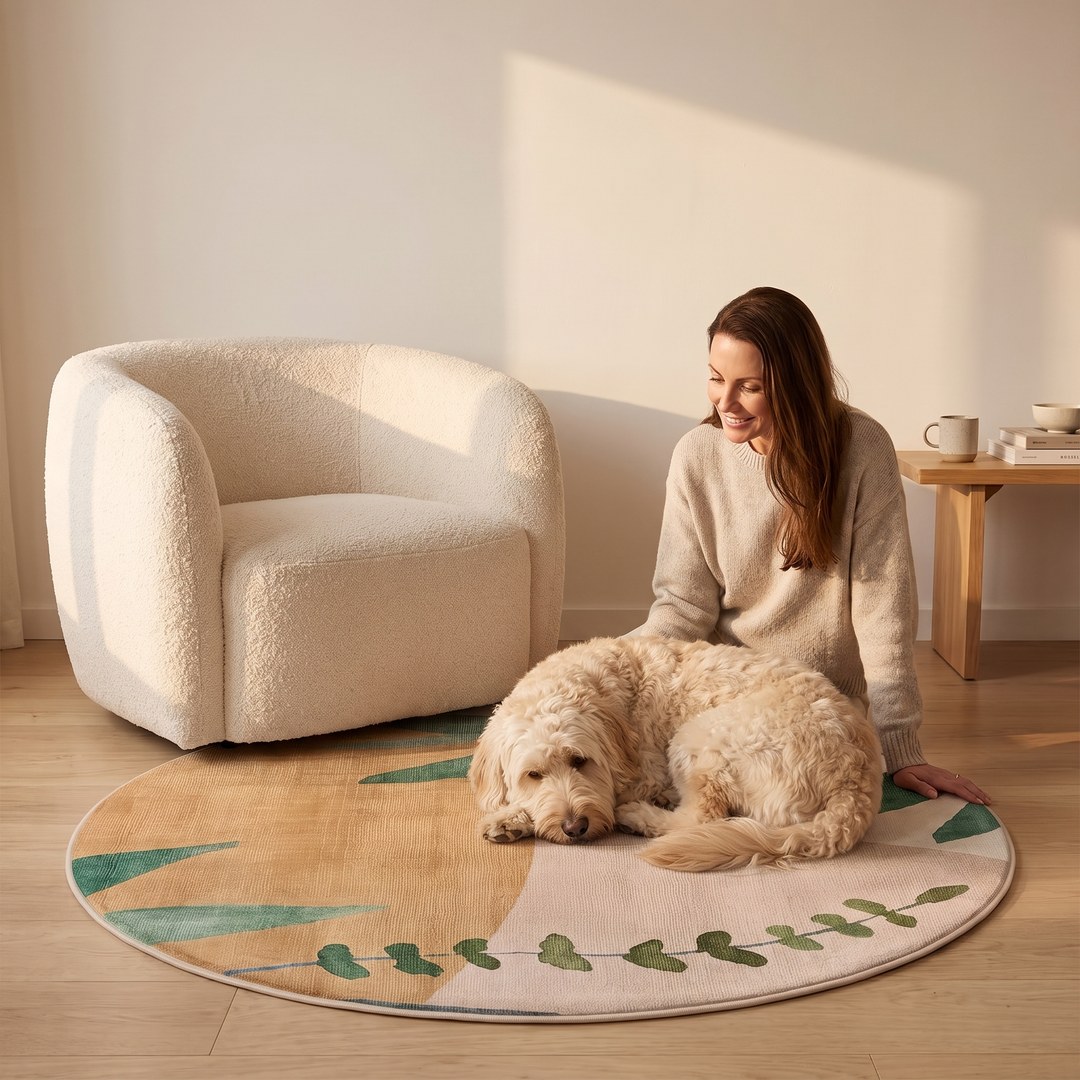 Round Rug – Leaf Print, Washable in Beige – Leaf – in a sunlit living room with a woman and dog