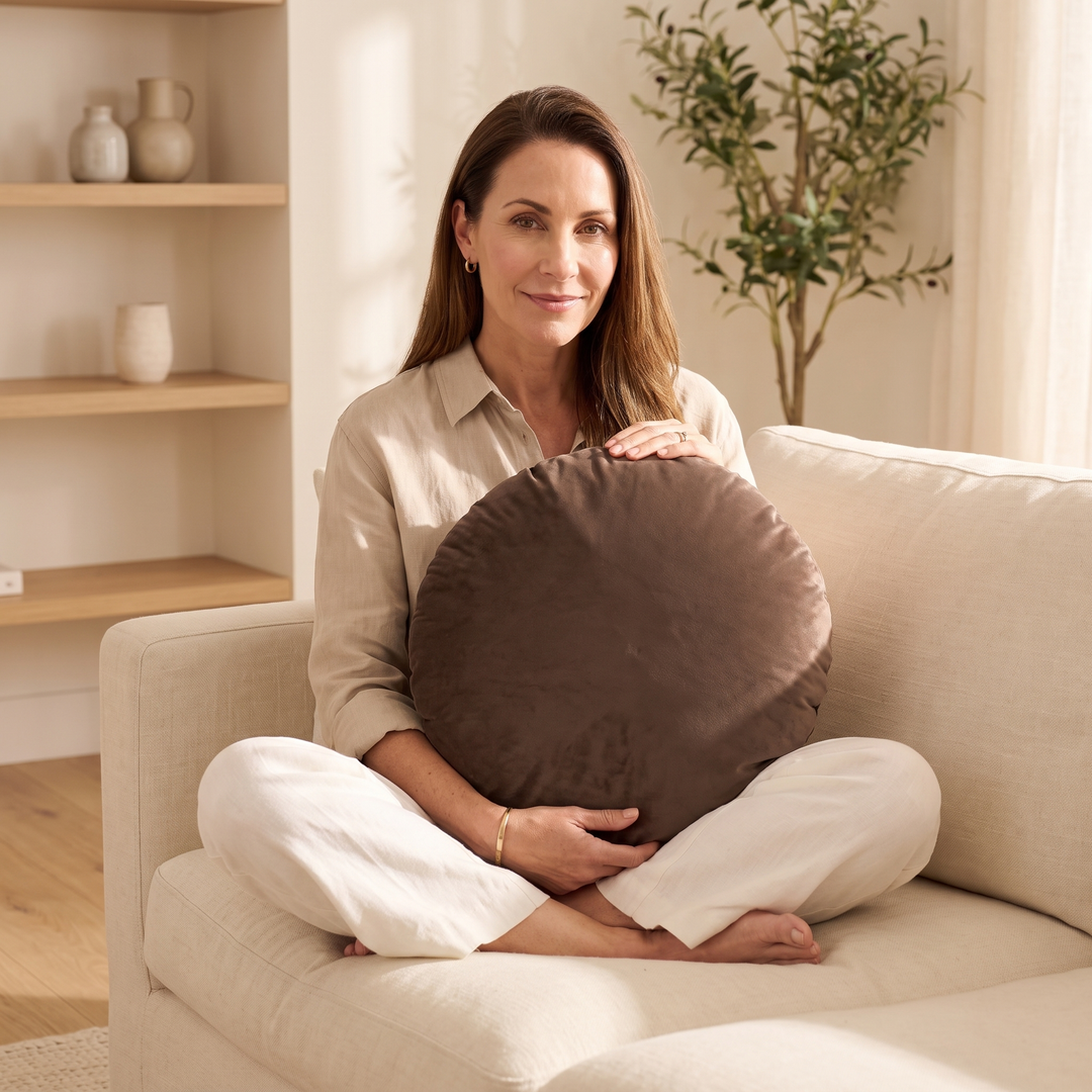 Round Velvet Pillow Cover in Chocolate Brown – held on lap by a woman sitting cross-legged