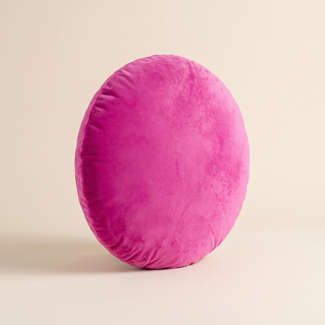 Round Velvet Pillow Cover in Fuchsia – standing on its rim with crushed velvet nap catching the light