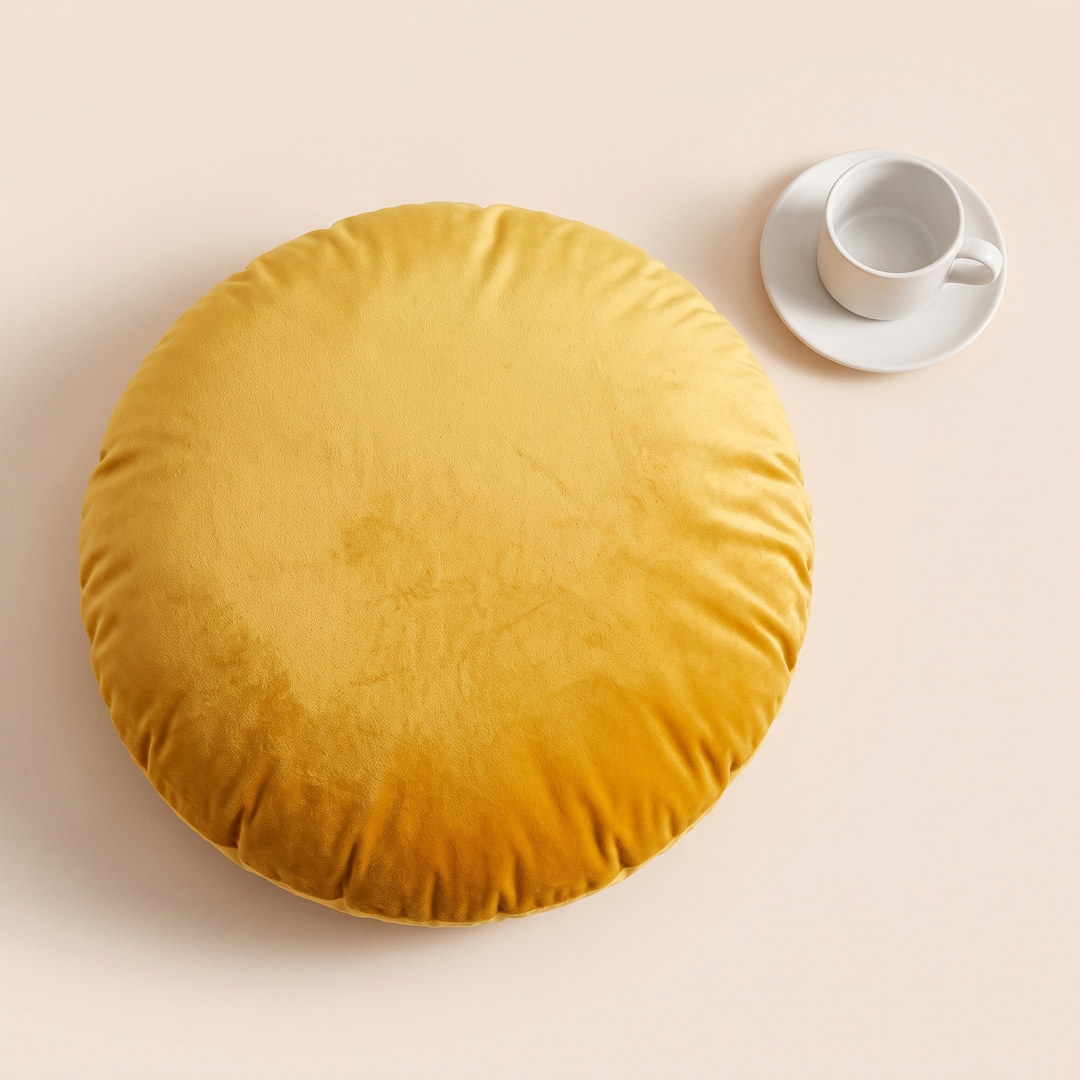 Round Velvet Pillow Cover in Golden Yellow – flat lay from above beside a white cup and saucer