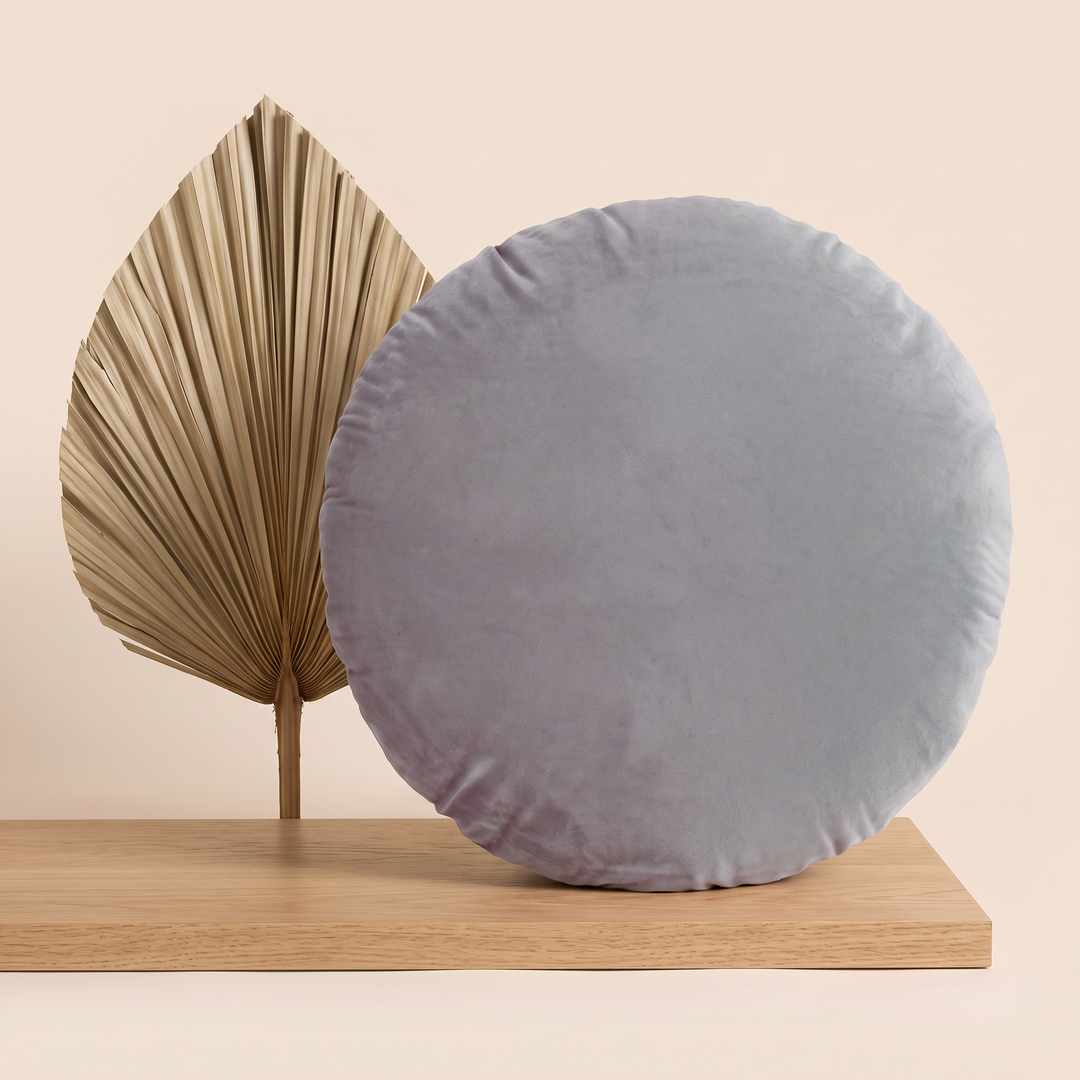 Round Velvet Pillow Cover in Gray – propped on an oak shelf beside a dried palm leaf