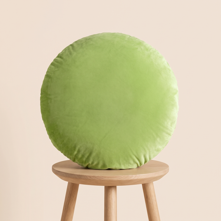 Round Velvet Pillow Cover in Lime Green – propped upright on a three-legged wooden stool