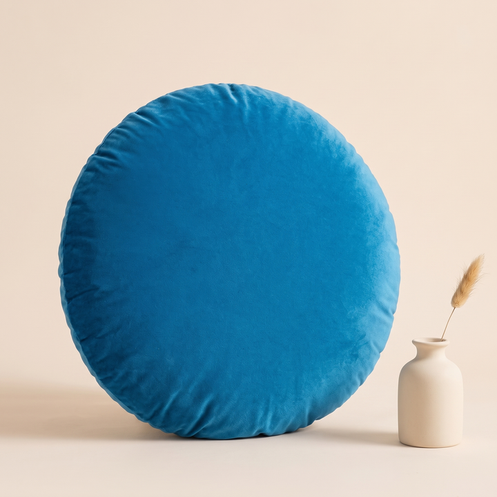 Round Velvet Pillow Cover in Peacock Blue – beside a small ceramic vase holding dried grass