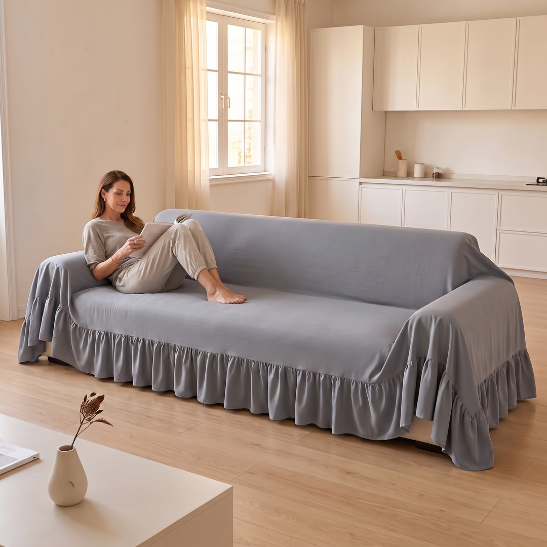 Ruffled Couch Cover in Gray – covering a three-seat sofa while a woman reads on it