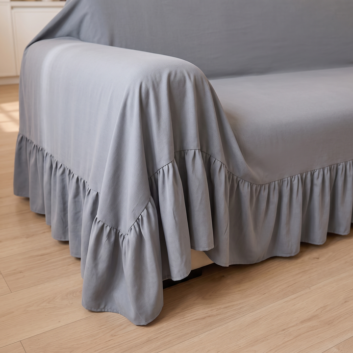 Ruffled Couch Cover in Gray – close-up of the ruffled hem over a sofa arm on wood flooring