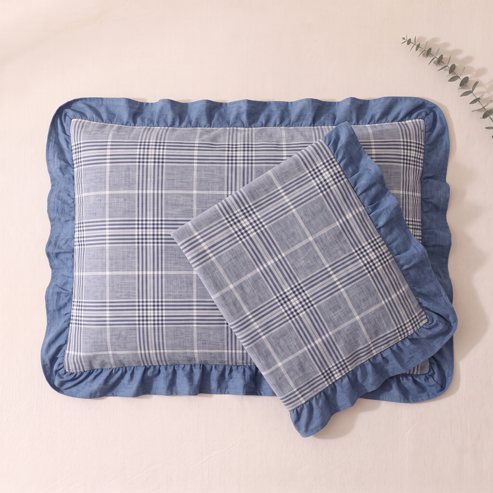 Cotton Pillowcases – Ruffled Plaid, Set of 2 in Blue Plaid – overhead, one case overlapping another, eucalyptus sprig at top right