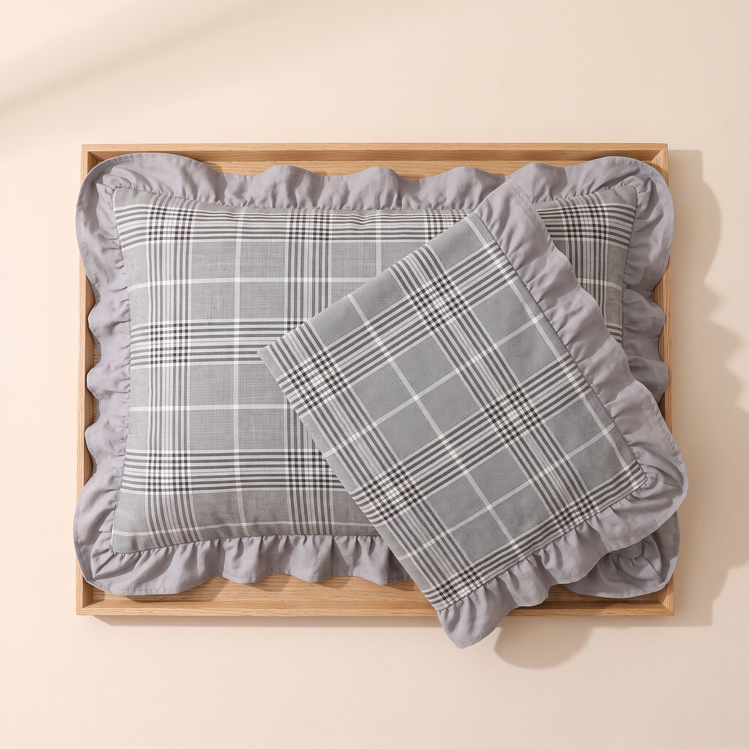 Cotton Pillowcases – Ruffled Plaid, Set of 2 in Gray Plaid – overlapping pair laid flat in a wooden tray, overhead view