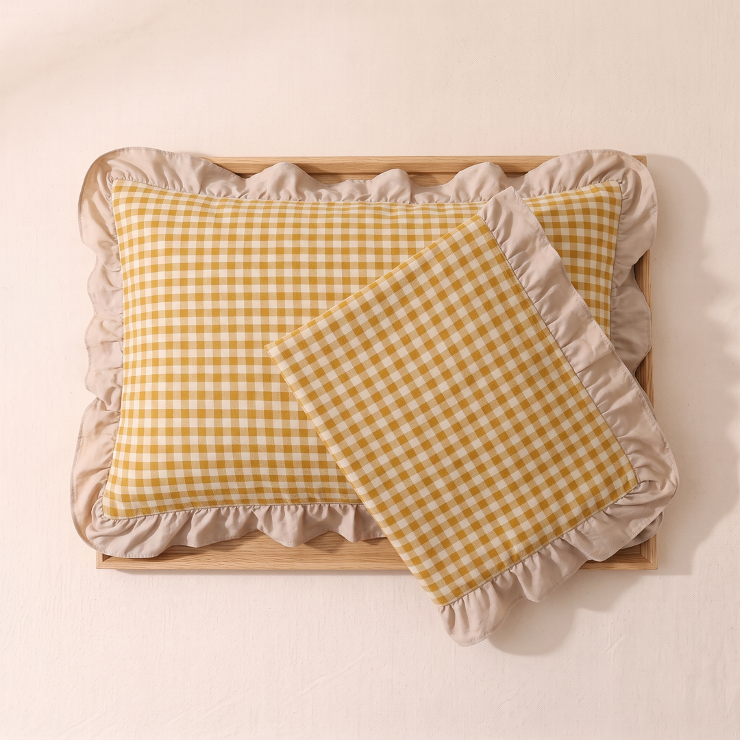 Cotton Pillowcases – Ruffled Plaid, Set of 2 in Mustard Gingham – one case tilted across another inside a light wood tray